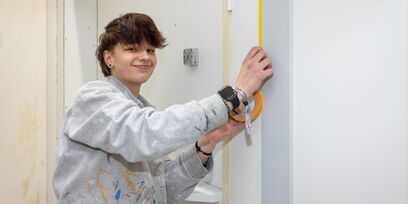 Student schilder verft binnenmuur met roller tijdens opleiding schilder