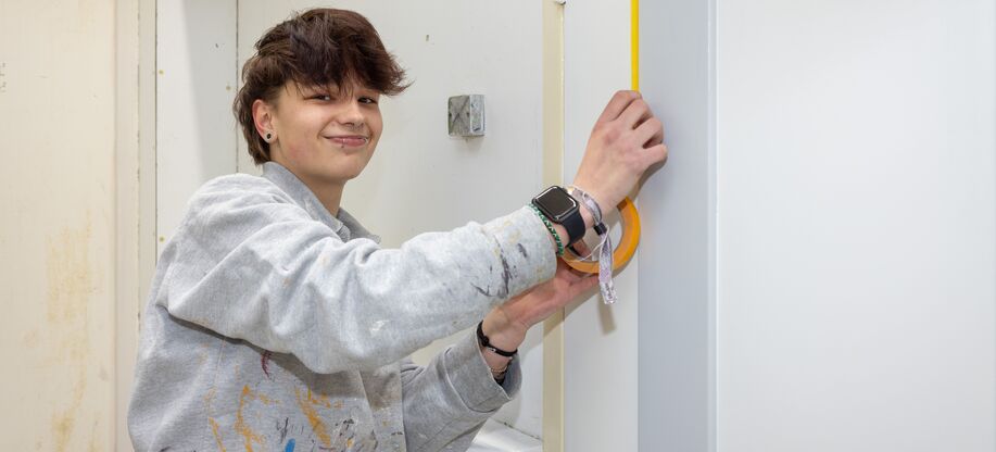 Student schilder verft binnenmuur met roller tijdens opleiding schilder