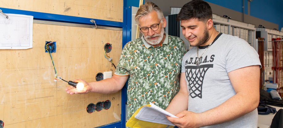 Docent monteur elektrotechniek geeft uitleg aan student.