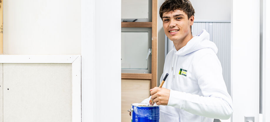 Studente opleiding schildert brengt verftape aan als voorbereiding op de schilderklus.