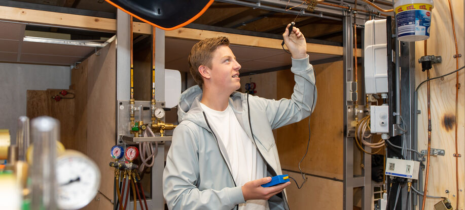 Student airco en warmtepompmonteur werkt aan een installatie op school 