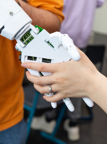 student geeft hand aan robot