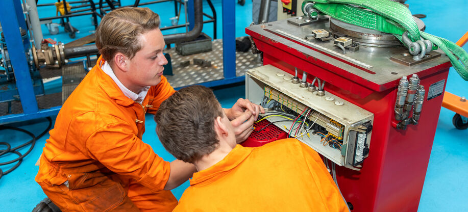 Twee studenten van de opleiding Eerste onderhoudsmonteur meet- en regeltechniek repareren een component.